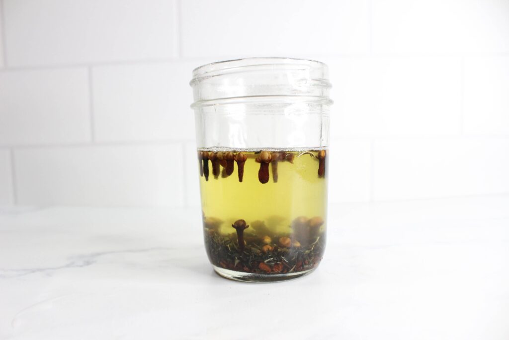 herbs and melted coconut oil in a glass jar