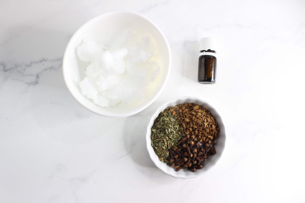 coconut oil, herbs and essential oil displayed on a white counter